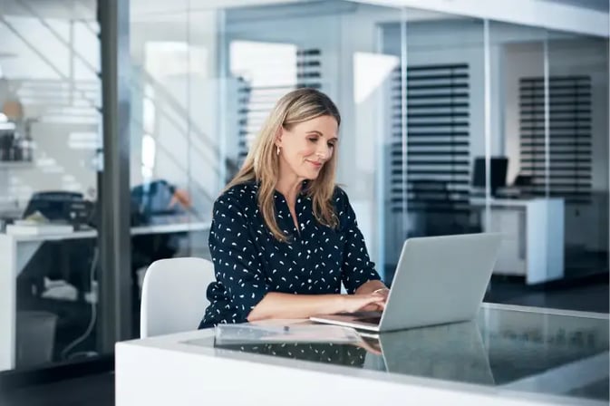 Female office worker using laptop at desk